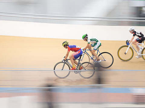 Trois cyclistes roulent sur la piste du Vélodrome Raymond Poulidor
